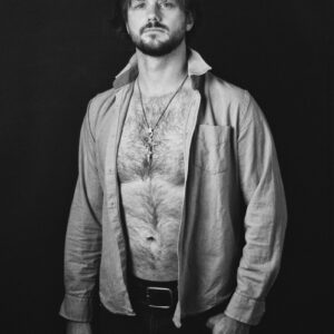 Man with open shirt and necklace against dark background