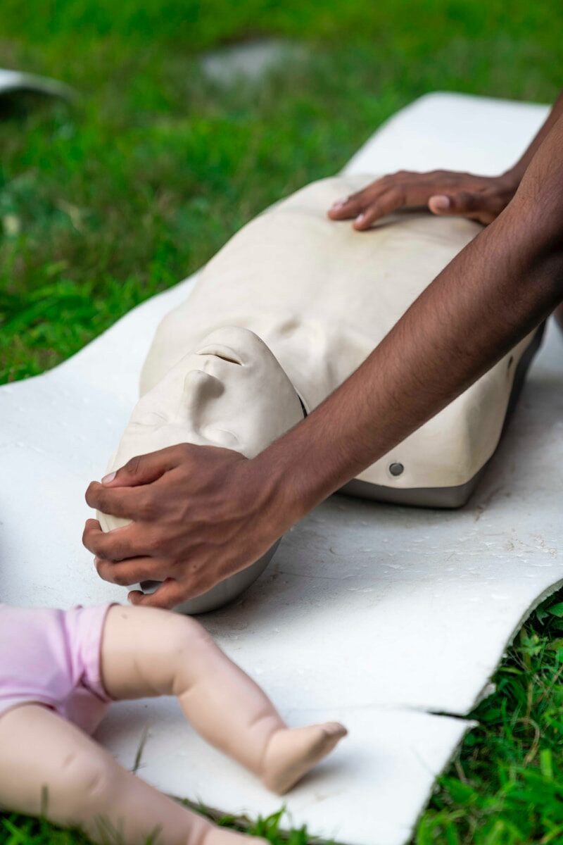 Hands practicing cpr on a training dummy outdoors
