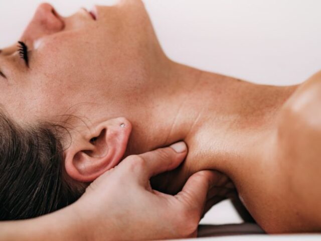 Therapist demonstrating neck and shoulder massage techniques taught on a massage therapy course